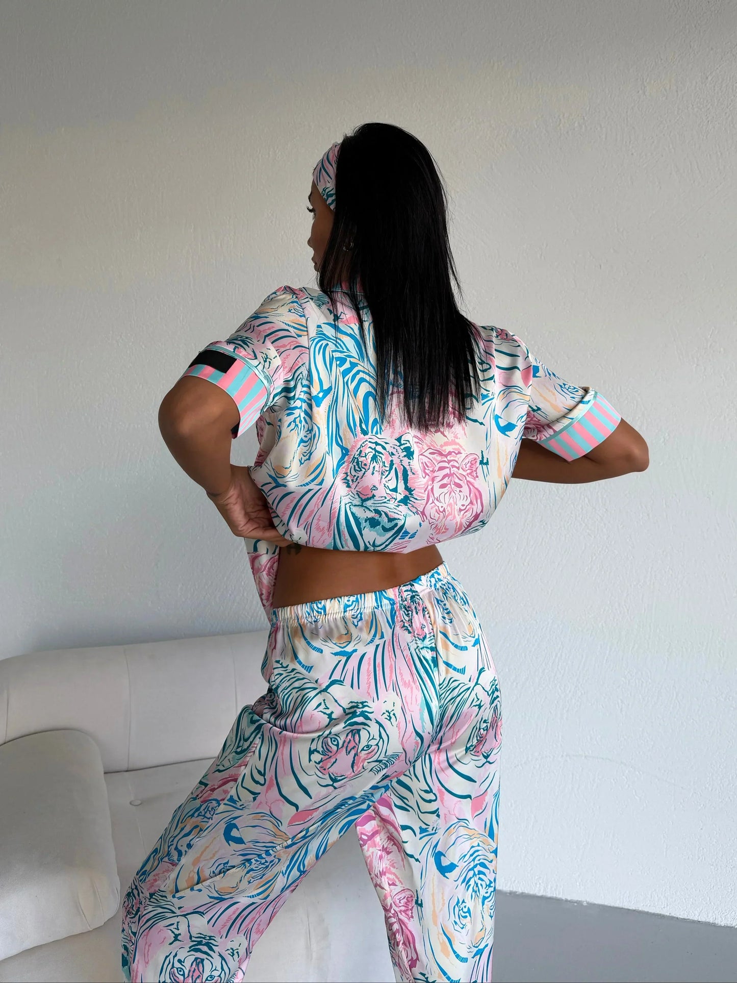 Woman wearing pastel tiger print pajama set with matching headband, standing indoors